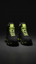 Chunky black streetwear boots with volt yellow accents, 3/4 angle product shots against deep matte black seamless or...